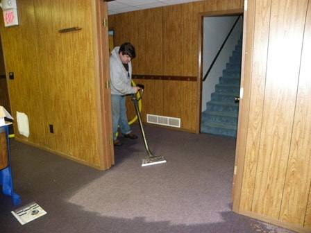 M-M Cleaning crew member actively extracting water from a flooded carpeted space